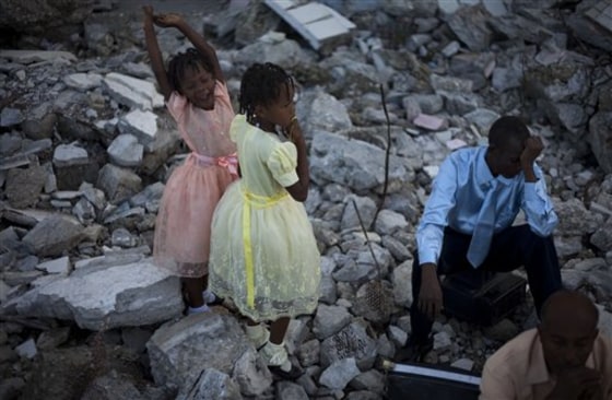 Antoine Fesnell, right, prays as his daughters Nicole, 9, center, and Antoine, 6, look on during mass in the rubble of the Notre Dame Cathedral in Port-au-Prince, Haiti, on Sunday. Fesnell's wife died in the earthquake that struck Haiti on Jan. 12 and killed a government-estimated 300,000 people and left millions homeless.